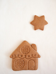 Gingerbread cookies in the shape of a house and stars on a white background