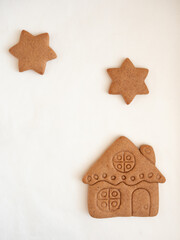 Gingerbread cookies in the shape of a house and stars on a white background