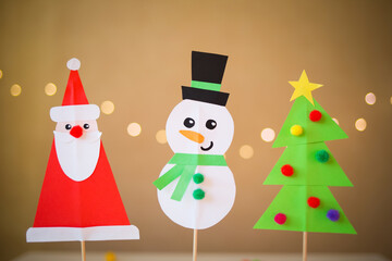paper craft for kids. snowman, Santa Claus and christmas tree on against background of yellow lights. create art for children. new year concept
