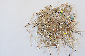 A pile of colorful glass head pins used for sewing, needlework and other projects and isolated on a white background. 