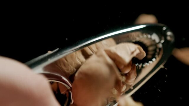 CLOSE UP: Crushing a walnut with a steel nutcracker. Slow motion.