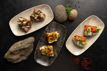 A set of three different types of bruschetta. Bruschetta with salmon and green butter, vegetables and cream cheese, bacon and sun-dried tomatoes.