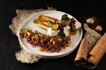 Veal tartare with pickled mushrooms and bruschetta with cream cheese, beef and quail egg. Cold raw meat dish with mushrooms.