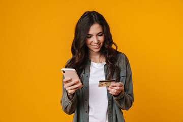 Fototapeta premium Happy beautiful nice girl holding credit card and mobile phone