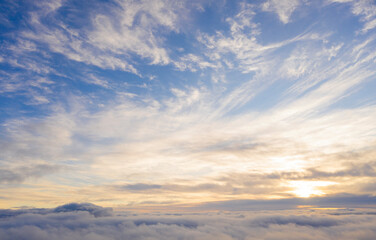Obraz premium Aerial view gold sunrise over clouds in blue sky. Aerial top view cloudscape. Texture of clouds. View from above. Orange sunrise or sunset over clouds. Panorama clouds texture