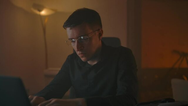 The man takes off his glasses, working in front of the laptop and doing himself an eye massage. Break in work, eyes should rest. Eye load problem from working behind LCD monitor