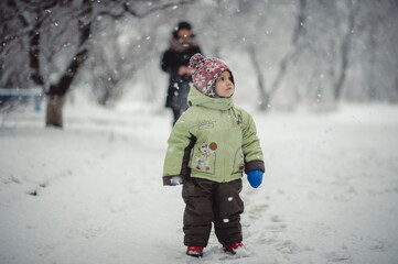 Fototapeta na wymiar Child in winter clothes and gloves walks among the winter landscape.