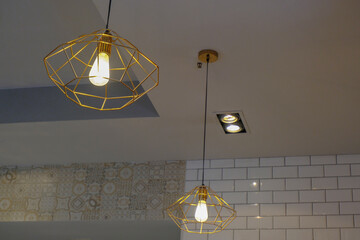 Golden colored metal lamps close-up on the ceiling across room interior. Interior design. Light...
