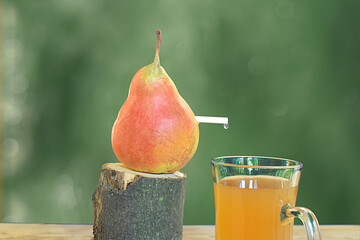 A pear and a straw from which juice is dripping into a glass. - Powered by Adobe
