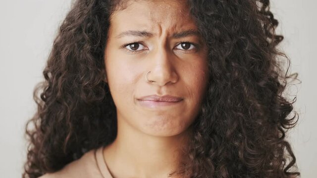 A close-up view of a serious african american woman is shaking her head negatively standing isolated over beige background