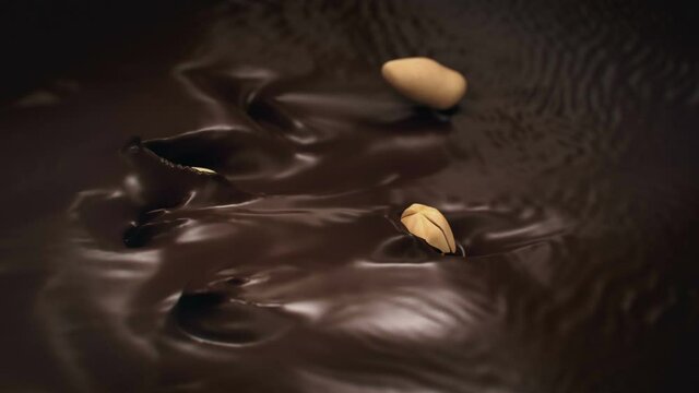 Peanuts Splashing Into Liquid Dark Chocolate in 4K Super slow motion