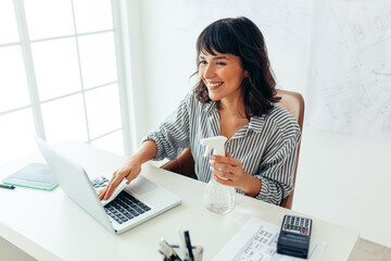 Obraz na płótnie Canvas Smiling woman entrepreneur wiping laptop with sanitizer