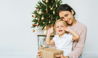 Happy Mom Gives Little Daughter a Christmas Present.Merry christmas and happy new year concept. Space for text. Family cozy moments.Morning before Xmas.