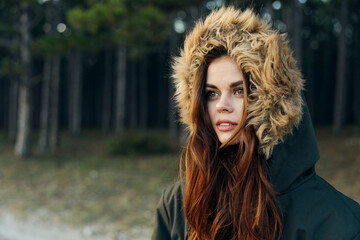 Woman tourist warm jacket with a hood on the nature against the background of trees