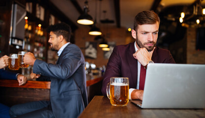 Handsome young business man, blogger or remote working with laptop in bar
