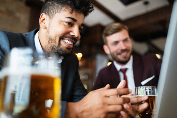 Happy young businessmen in suits are smiling and talking in a restaurant