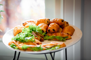 Chocolate puff pastry buns on restaurant buffet catering table. Catering buffet table with a delicious food. Stacks of croissant sandwich at wedding