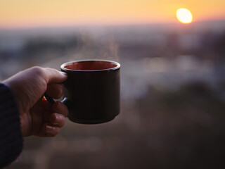 Mug of hot coffee at sunset