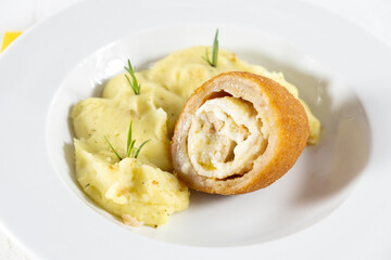 Chicken Kiev cutlet with mashed potatoes and slice on a plate, white background