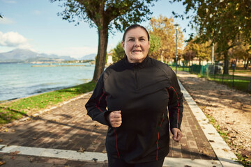 Active senior woman doing healthy exercises outdoors. Jogging