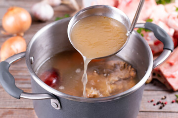 Saucepan with bouillon with a ladle. Bone broth - obrazy, fototapety, plakaty