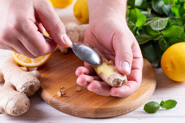 Man peeling ginger with a spoon on a wooden table