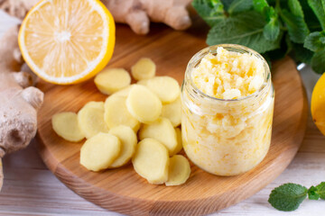 Alternative medicine, natural home remedy for cold and flu. Glass jar with honey, lemon and ginger on wood table