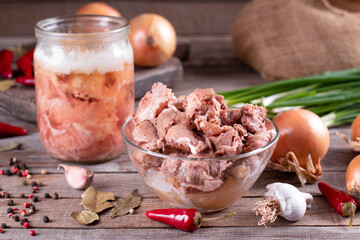 Stew homemade meat in glass jar with spices on wooden background