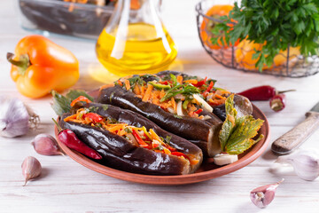 Pickled stuffed eggplant with vegetables in a plate on a wooden table