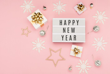 Happy New Year text on white Lightbox with gift boxes, holiday silver and gold decorations,...