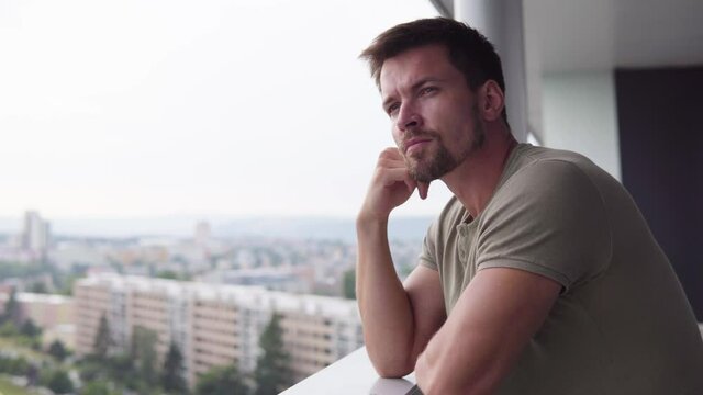 A young handsome man looks thoughtfully out of a balcony in a luxurious apartment - closeup