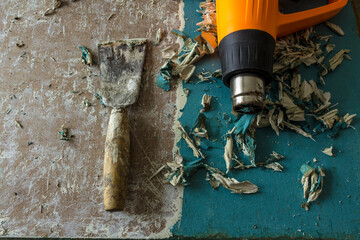 Restoration of an old door. Removing old paint coats with a heat gun and a spatula. View from above .Twisted pieces of blue paint and old white putty.