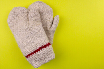 Knitted warm mittens on a yellow background