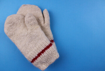 Knitted warm mittens on a blue background