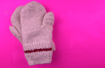 Knitted warm mittens on a pink background