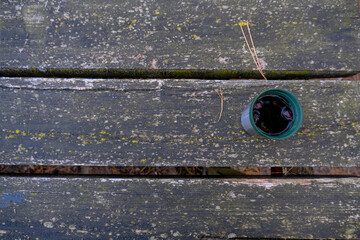 Hot tea in plastic thermo mug on wooden background close-up. Top. Copy space. Hot beverage outdoors. camping, trekking, travel concept. 
