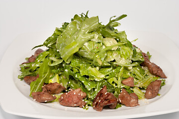 Chicken liver salad lettuce leaves on white plate