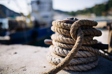 Fototapeta premium Querer-Song9old rope knotted at the boat dock, in the background a fishing cutter