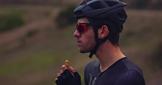 Professional cyclist eating snack bar on top of mountain