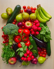 Raw fresh vegetables and fruits background. Healthy food flat lay on wooden background. Assortment of organic food: tomato, radish, broccoli, apple, banana, rucola, red onion