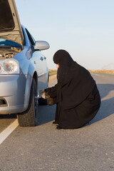 Muslim woman driver changes car wheel