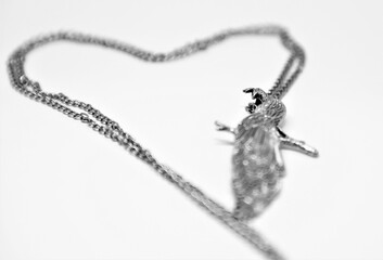 Black and white photo of a chained A beautiful peacock shaped pendant creating a heart shape on...