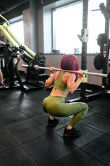Fototapeta premium woman doing squats workout at gym. Legs training with barbell