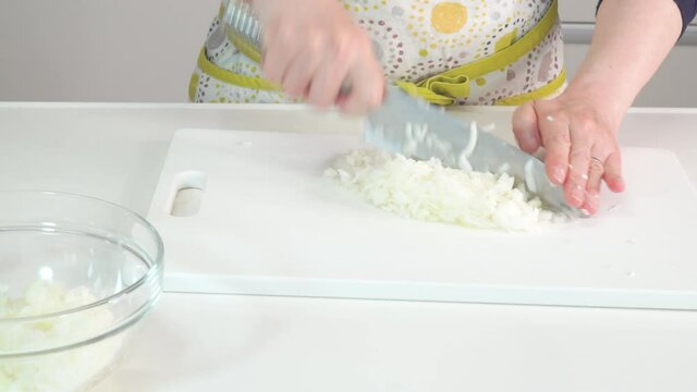 玉ねぎをみじん切りにしていく主婦の調理シーン