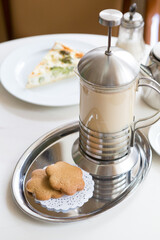 Tea with milk served in french press with cookies
