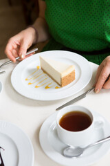Woman eating cheese cake with cup of tea