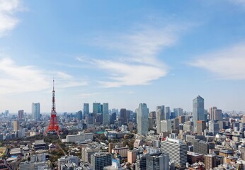 Obraz premium Beautiful city skyline of Downtown Tokyo, with the famous landmark Tokyo Tower standing tall among crowded skyscrapers under blue sunny sky in Tokyo, Japan. Aerial view of busy Tokyo City