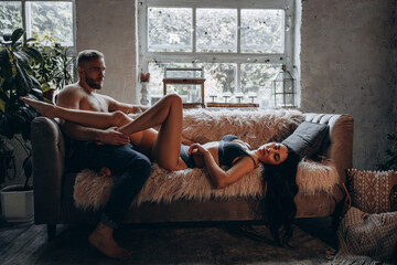 Romantic intimate photo session of a young couple. The guy and the girl spend time together. A love story in a cozy home environment.