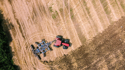 Aerial view of tractor or combine harvester works in field. Industrial agriculture