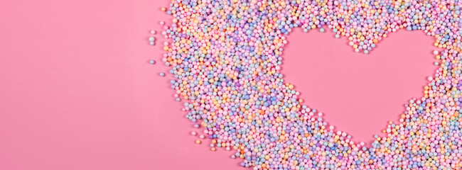 Heart frame made of pastel color balls on pink. Styrofoam or Polystyrene foam background. Mixed...